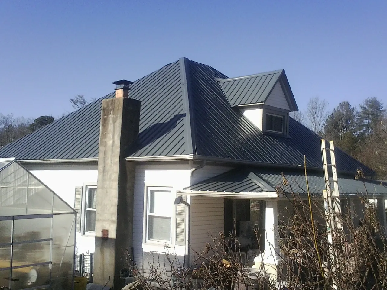 Dark blue standing seam metal roof on a white farmhouse with dormer — Slate & Tile Roof Repair by Roofing Brothers in Shade Gap