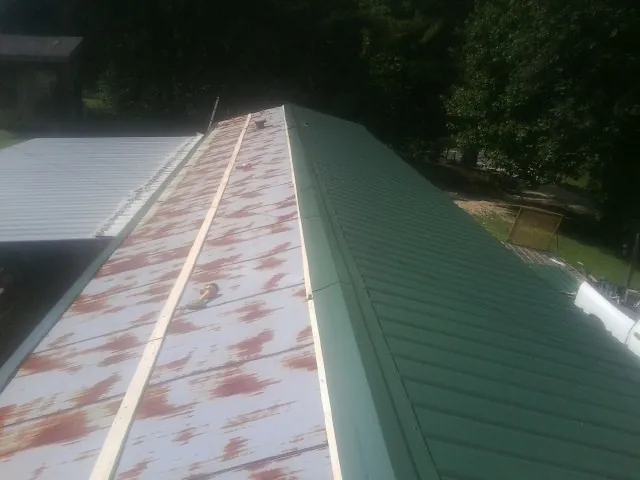 Old rusted panels beside newly installed green metal roofing — Wind Damage Roof Repair by Roofing Brothers in Shade Gap