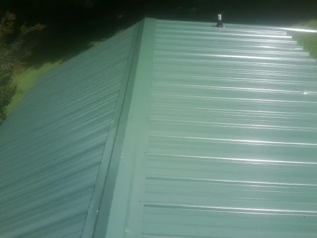 New green metal panels meeting at the ridge of a roof — Flat Roof Repair work by our crew in Shade Gap