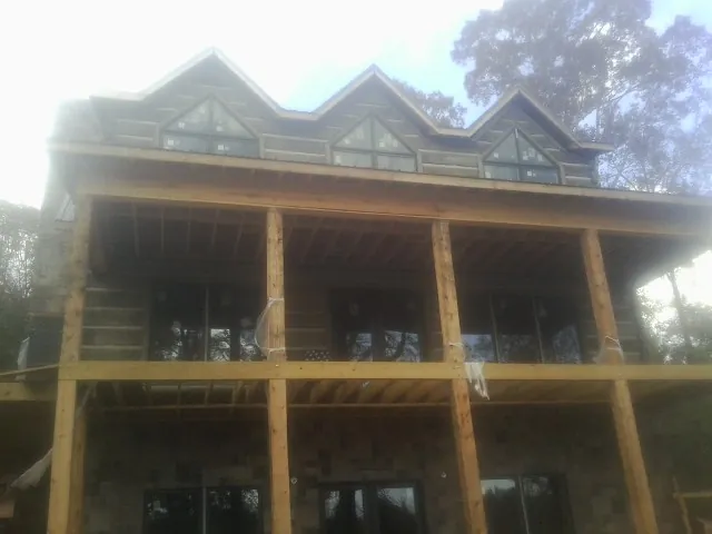 Dormers and porch framing on a large log home under construction — Roof Coating work by our crew in Shade Gap