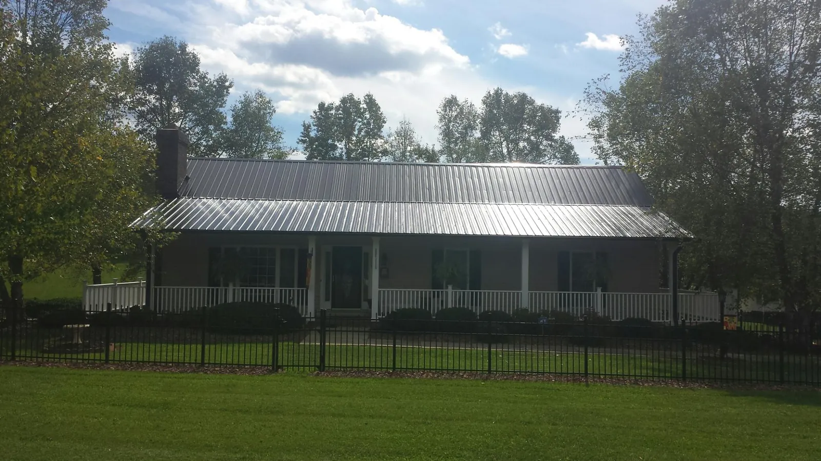 Gray metal roof on a brick ranch with a full width front porch — Gutter Guard Installation work by our crew in Shade Gap