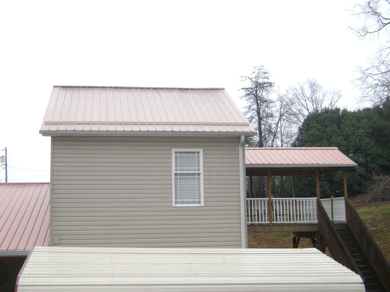 Tan metal roofs on a two story addition and attached porch, from a Roof Replacement job in Shade Gap