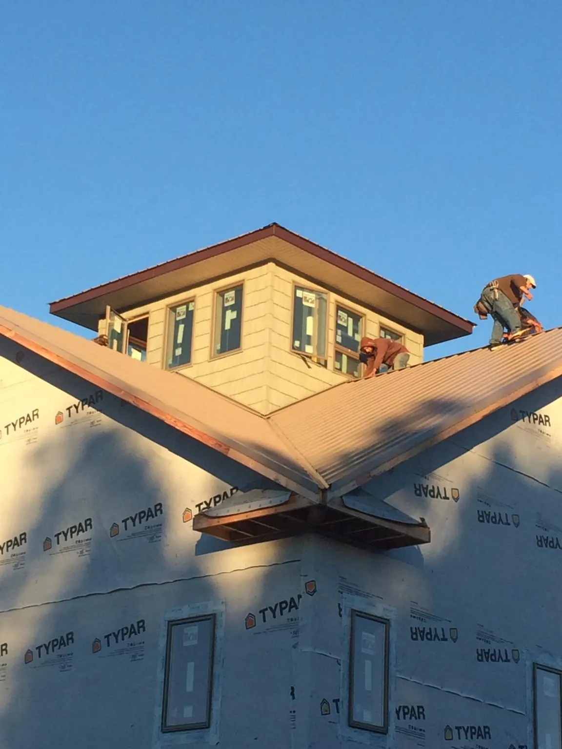 Roofers working around a rooftop cupola on a new metal roof at sunset — Roof Waterproofing in Shade Gap by Roofing Brothers